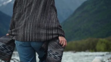 Genç çekici kız gezgin-blogger ellerini kaldırır, dağların görünce sevinir. Sıcak giysiler ve ekose giymiş. Bir dağ nehri boyunca yürümek. Svaneti, Gürcistan