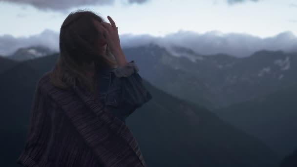 山を背景に若いロマンチックな女の子の肖像画。雪に覆われた山々の後ろの夕日を見る美しい少女。悲しいまたは考える — ストック動画