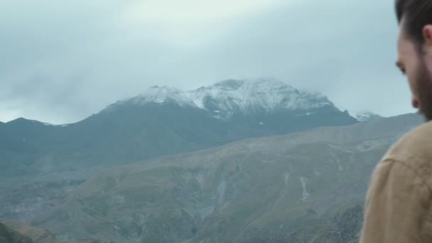 Homme photographe voyageur fait des photos professionnelles de montagne pour le blog. Un type aux cheveux longs et à la barbe tenant une caméra professionnelle dans ses mains. Expédition dans les montagnes — Video