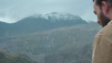Erkek gezgin fotoğrafçı blog için profesyonel dağlar resimleri yapar. Elinde profesyonel bir kamera tutan uzun saçlı ve sakallı bir adam. Dağlara sefer