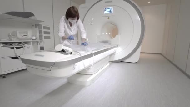 Az orvos MRI vizsgálatot végez egy betegnél a klinikán. A lány az MRI-ben fekszik. Mágneses rezonanciás képalkotás az emberi test tanulmányozásában. Modern technológiák az orvostudományban — Stock videók