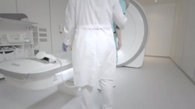 Doktor klinikteki bir hasta için MRI taraması yapıyor. Kız MRI cihazında yatıyor. İnsan vücudu çalışmasında manyetik rezonans görüntüleme. Tıptaki modern teknolojiler