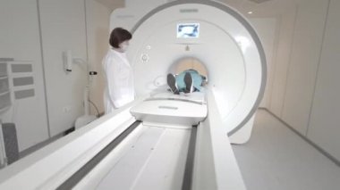 Doktor klinikteki bir hasta için MRI taraması yapıyor. Kız MRI cihazında yatıyor. İnsan vücudu çalışmasında manyetik rezonans görüntüleme. Tıptaki modern teknolojiler
