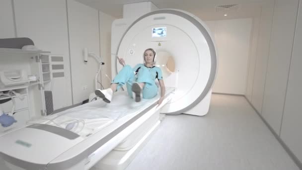 Az orvos MRI vizsgálatot végez egy betegnél a klinikán. A lány az MRI-ben fekszik. Mágneses rezonanciás képalkotás az emberi test tanulmányozásában. Modern technológiák az orvostudományban — Stock videók