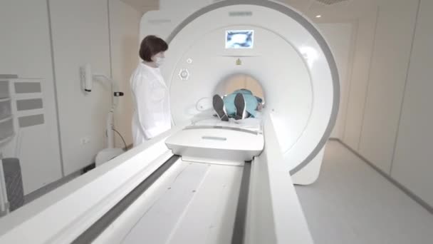 Doktor klinikteki bir hasta için MRI taraması yapıyor. Kız MRI cihazında yatıyor. İnsan vücudu çalışmasında manyetik rezonans görüntüleme. Tıptaki modern teknolojiler — Stok video