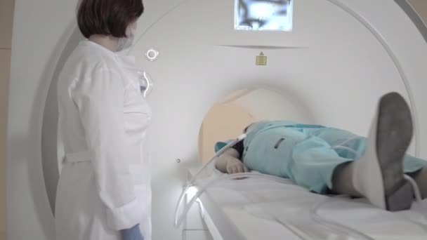 El médico realiza una resonancia magnética para un paciente en la clínica. La chica yace en el dispositivo de resonancia magnética. Imágenes por resonancia magnética en el estudio del cuerpo humano. Tecnologías modernas en medicina — Vídeo de stock