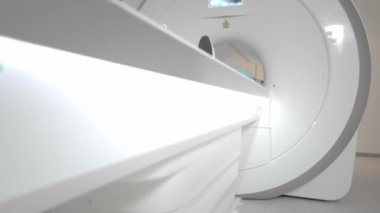 Doktor klinikteki bir hasta için MRI taraması yapıyor. Kız MRI cihazında yatıyor. İnsan vücudu çalışmasında manyetik rezonans görüntüleme. Tıptaki modern teknolojiler