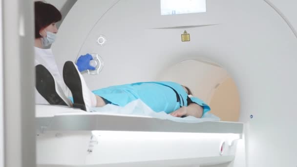 Врач делает МРТ для пациента в клинике. Девушка лежит в аппарате МРТ. Магнитно-резонансная томография при изучении человеческого тела. Современные медицинские технологии — стоковое видео