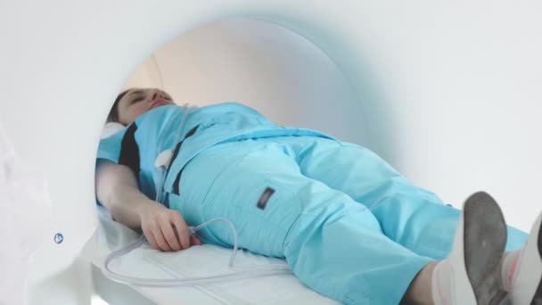 医者は診療所で患者のMRI検査を行う。少女はMRI装置に横たわっている。人間の体の研究で磁気共鳴画像。医学における近代技術 — ストック動画