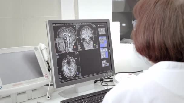 Doktor teknisyen MRI taramasını izliyor. İnsan vücudu çalışmasında manyetik rezonans görüntüleme. Uzman, laboratuvardaki monitöre bakıyor. — Stok video