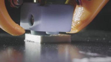 3D yazıcı, plastik karın kaslarından soyut bir küp şeklinde basıyor. 3D yazıcı başı devrede. Otomatik üç boyutlu bir 3D yazıcı plastik işlevi görür. Makro.