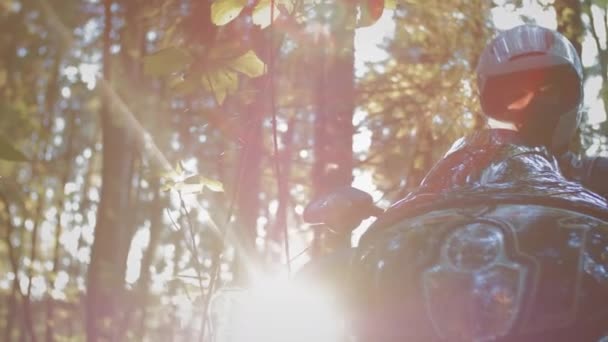 Motociclista homem romântico motociclista senta-se em uma motocicleta na floresta. Inclui farol de motocicleta. A lanterna acende-se. Preparação para uma viagem de bicicleta — Vídeo de Stock