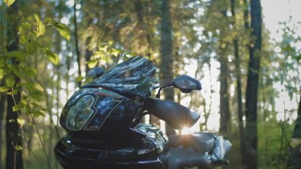 Motorradfahrer sitzt auf einem Motorradsitz. Schaltet das Fahrrad ein oder startet es. Vorbereitungen für eine Radtour. Bei Sonnenuntergang im Wald — Stockvideo
