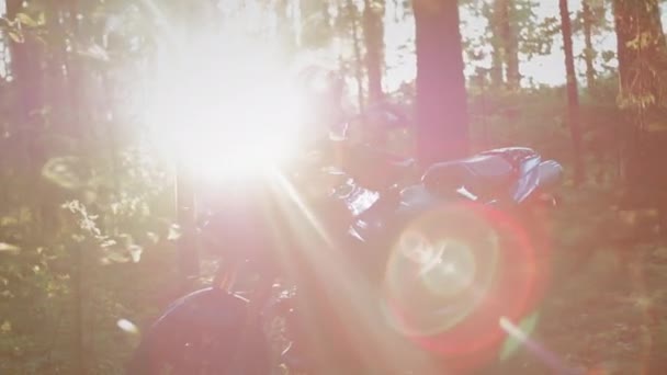Μοτοσικλετιστής ποδηλάτης κάθεται σε ένα κάθισμα μοτοσικλέτας. Ενεργοποιεί ή ξεκινά το ποδήλατο. Προετοιμασία για ένα ταξίδι με ποδήλατο. Το ηλιοβασίλεμα στο δάσος — Αρχείο Βίντεο