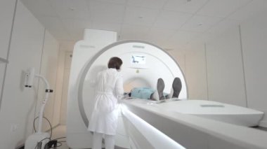 Doktor klinikte bir hasta için MRI taraması yapar. Kız MRI cihazında yatıyor. İnsan vücudu çalışmasında manyetik rezonans görüntüleme. Tıptaki modern teknolojiler. Ciğerleri inceler.