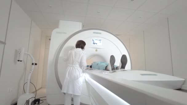 医者は診療所で患者のMRIスキャンを行います。少女はMRI装置に横たわっている。人間の体の研究で磁気共鳴画像。医療における近代技術。肺を検査する. — ストック動画