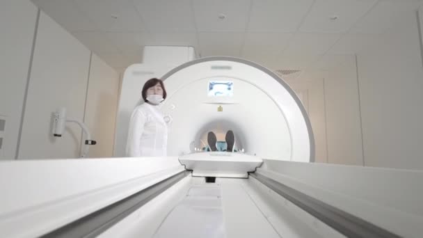 De dokter maakt een MRI scan voor een patiënt in een kliniek. Het meisje ligt in het MRI apparaat. Magnetische resonantie beeldvorming in de studie van het menselijk lichaam. Moderne medische technologie. Onderzoekt longen. — Stockvideo