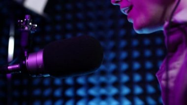 Güzel genç kız DJ mikrofona konuşuyor, podcast 'i kaydediyor ya da radyo için sabah haberlerini sunuyor. Podcast sunucusunun ya da DJ 'in mikrofondaki konuşmasını kapat. Profesyonel kulaklık takıyor..