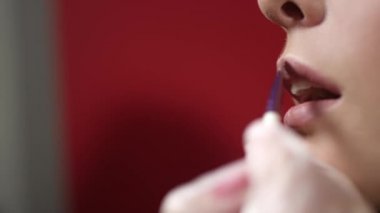 Genç bir kadın dudaklarını rujla boyuyor. Makyaj yapan güzel bir model. Kadın kameradan önce makyaj yapıyor. Defileye ya da çekimlere hazırlanıyor. Dolgun dudaklara ruj sürüyor. Kozmetik kavramı.