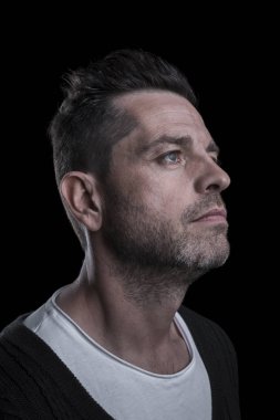 Yukarı bakan ciddi bir adamın portresi. Siyah arka plan. Dikey.