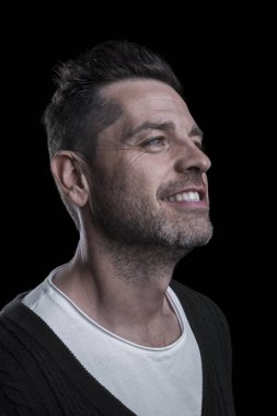 Yukarı bakan gülümseyen bir adamın portresi. Siyah arka plan. Dikey.