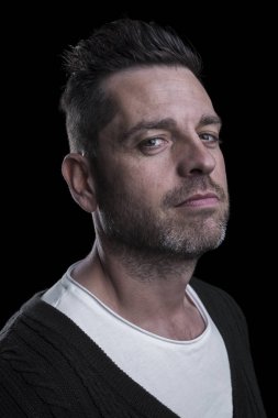 Kameraya bakan beyaz bir adamın portresi. Siyah arka plan. Dikey. Closeup.