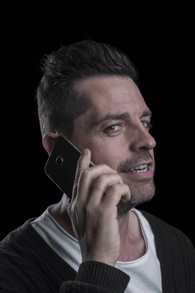 Портрет мужчины с мобильным телефоном, смотрящего в камеру. Чёрный фон. Вертикаль . — стоковое фото
