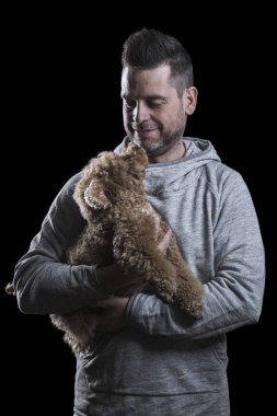 Küçük kırmızı bir oyuncak kanişçiye bakan bir adamın portresi. Siyah arka plan. Dikey.