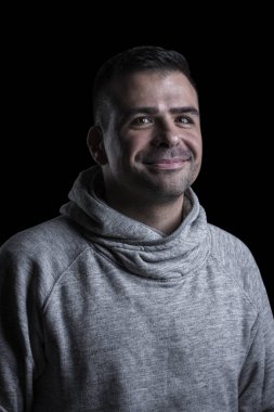 Kameraya bakan gülümseyen bir adamın stüdyo portresi. Siyah arka plan.