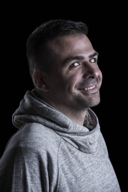 Kameraya bakan gülümseyen bir adamın portresi. Siyah arka plan.