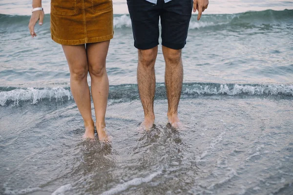 Hermosa pareja cogida de la mano y camina en la orilla del mar — Foto de Stock