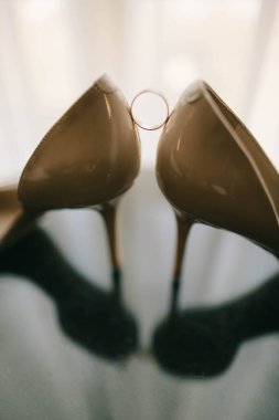 Düğün ayakkabıları ve yüzükler cam masada.