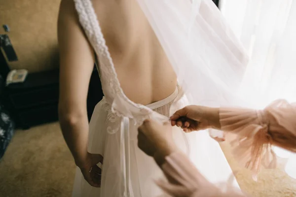 Мама допомагає доньці одягнути весільну сукню — стокове фото