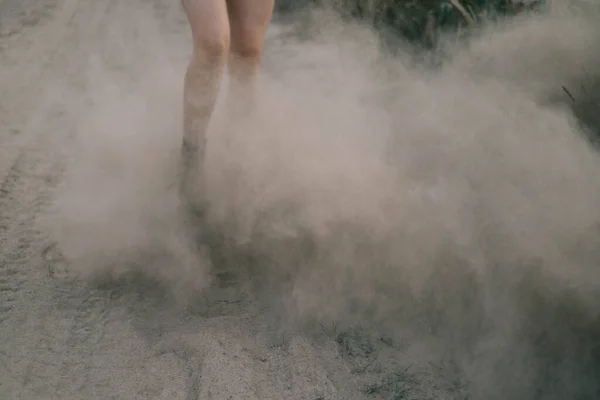 Vrouwelijke benen springen in de woestijn door fijn stof met stofwolken — Stockfoto