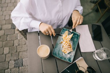 Bir kızın nasıl pasta yediğinin ve bardaklı kahve içtiğinin ve arka planda bir moda dergisinin.