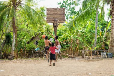 Sandugan, Siquijor, Filipinler - 13 Mayıs 2013: kum alan eski ahşap basketbol sepeti ile basketbol oynayan üç çocuk