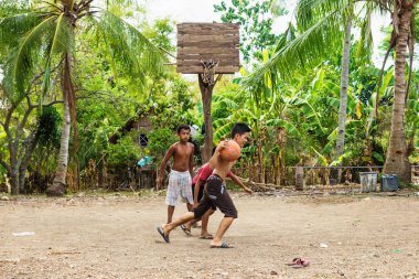 Sandugan, Siquijor, Filipinler - 13 Mayıs 2013: üç çocuk basketbol oynarken eski ahşap basketbol sepeti ile kum Field'da floplar flip