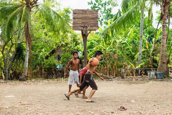Sandugan, Siquijor, Filipinler - 13 Mayıs 2013: üç çocuk basketbol oynarken eski ahşap basketbol sepeti ile kum Field'da floplar flip