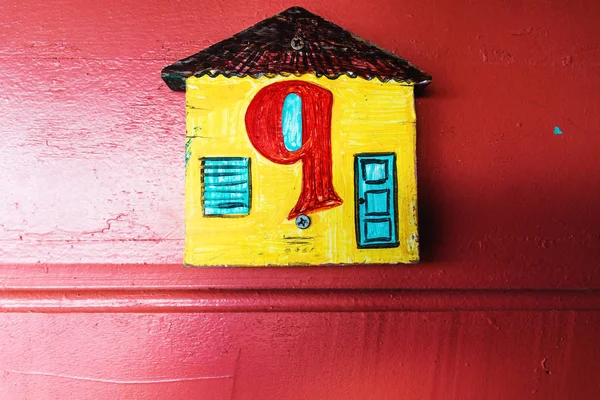 Number nine with arabic letters and maya letters in a yellow house with red wooden wall, Belize