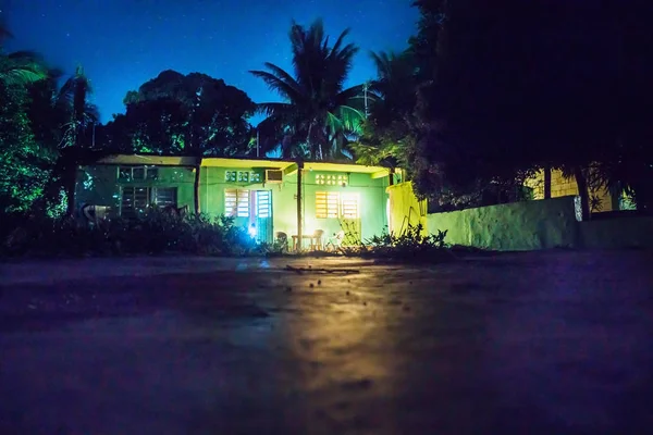 Backyard at night with green house and lightened rooms and terrace, Bacalar, Mexico