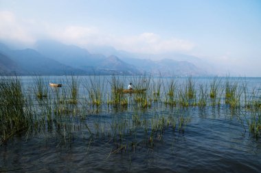 Kano ile balıkçı reed ile Lago Atitlan, San Juan la Laguna, Guatemala, Orta Amerika, Puslu Dağlar ardında