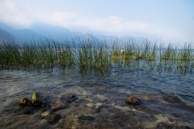 Reed ile Lago Atitlan, San Juan la Laguna, Guatemala, Orta Amerika, Puslu Dağlar arkasında tekne