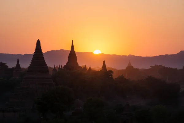 Silhouettes of Burmese Pagodas while sun is setting in the mountains, Bagan, Myanmar — Stock Photo, Image