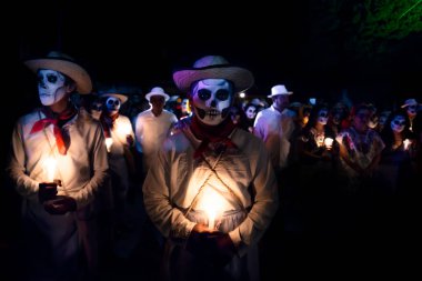 Merida, Cementerio genel, Meksika - 31 Ekim 2018: iki beyaz beyaz şapka ve kırmızı eşarp ile customed çocuklar ve kafatası makyaj holding mumlar önünde bekleyen geçit töreni kostümlü insanlar lighented ile dia de l için Event'de mavi ve pembe ışık tarafından