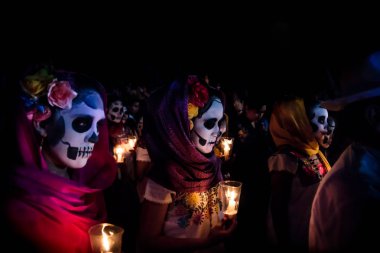 Merida, Cementerio genel, Meksika - 31 Ekim 2018: Catrina customes, eşarp baş ve kafatası makyaj holding candels saçına çiçekler üzerinde üç kadınla muertos Festiv adlı dia de los için geçit töreninde kostümlü insanlar tarafından çevrili