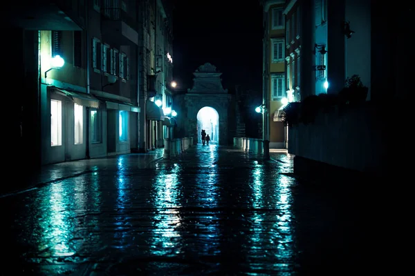 Silhouttes caminando por el arco en calles empedradas mojadas en Zadar, Croacia — Foto de Stock