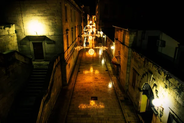 Silhouttes wandelen langs de komst ingericht geplaveide straten van Zadar bij nacht, Kroatië — Stockfoto