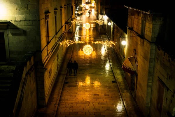 Primer plano de silhouttes caminando a lo largo de las calles adoquinadas decoradas de Navidad de Zadar por la noche, Croacia — Foto de Stock