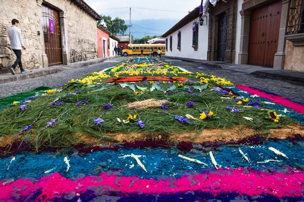 Alfombre çiçek halı Antigua, Guatemala yolun sonundaki sarı bir okul otobüsü ile Arnavut kaldırımlı sokaklarda