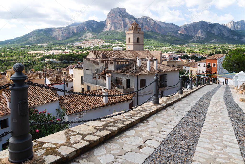 Street to the village and church of Polop de Marina with rocky mountainrange, Costa Blanca, Spain